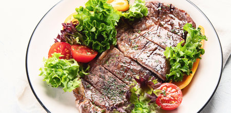 Grilled beef steak and fresh vegetables with salad on plate on a white background. Top view.の写真素材