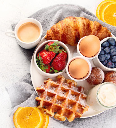 Breakfast table with eggs, berries, yogurt, waffle and croissant. Breakfast concept. Top viewの写真素材