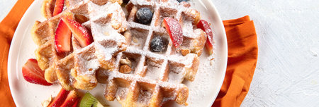 Waffles sprinkled with powdered sugar with strawberries and cherries on a white background. Top view. Panorama with copy space.の写真素材