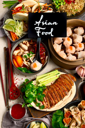 Set of Chinese dishes on dark background: sweet duck, soup, steamed buns, dim sum in bamboo steamer, salad, rice, dips. Asian style banquet, top view.の写真素材
