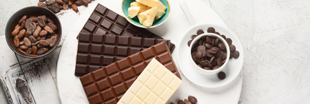 Dark bitter, milk and white chocolate, cocoa butter, cocoa powder and beans on a gray background. Top view. Panorama with copy space.の写真素材