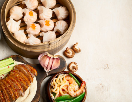 Set of Chinese dishes on dark background: sweet duck, soup, steamed buns, dim sum in bamboo steamer, salad, rice, dips. Asian style banquet, top view. Panorama with copy space.の写真素材