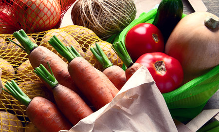 Raw vegetables in eco bags, carrots, apples, onion, garlic, potatoes. Zero waste concept. Free plastic shopping and reuse. Top view. Panorama.の写真素材