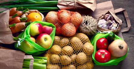Raw vegetables in eco bags, carrots, apples, onion, garlic, potatoes. Zero waste concept. Free plastic shopping and reuse. Top view. Panorama.の写真素材
