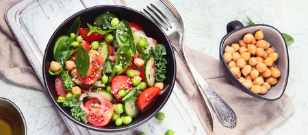 Vegan salad with cucumber, tomato, spinach, lettuce, onion, green pea and chickpea. Healthy eating. Top view. Panorama.の写真素材