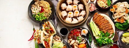 Set of Chinese dishes on dark background: sweet duck, soup, steamed buns, dim sum in bamboo steamer, salad, rice, dips. Asian style banquet, top view. Panorama with copy space.の写真素材