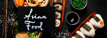 Assorted gourmet Japanese dishes. Set of sushi, rolls, soup and rice on a black background. Top view. Panorama.の写真素材
