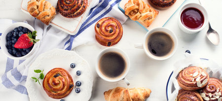 Traditional breakfast with buns, croissants and coffee on a white background. Top view. Panorama.の写真素材