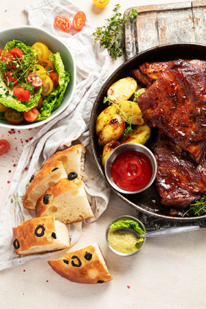 Tasty roasted ribs with baked potatoes vegetables and olives on a white background. Top view.の写真素材