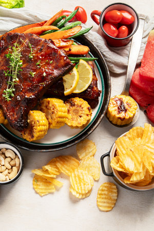 BBQ ribs with vegetables, sauce, roasted corn and watermelon on a white background. Top view.の写真素材