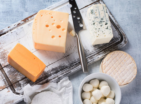 Different kinds of cheeses on rustic wooden board. Top view.の写真素材