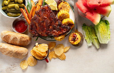 BBQ ribs with vegetables, sauce, roasted corn and watermelon on a white background. Top view.の写真素材