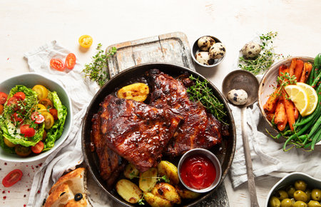 Tasty roasted ribs with baked potatoes vegetables and olives on a white background. Top view. Copy space.の写真素材