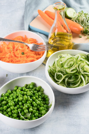 Fresh carrot, green peas and cucumber on a blue background. Vegan food concept. healthy eating. Top view.の写真素材