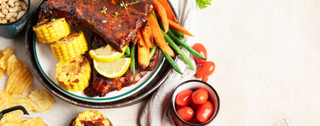 BBQ ribs with vegetables, sauce, roasted corn and watermelon on a white background. Top view. Panorama with copy space.の写真素材