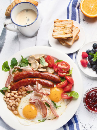 Traditional full english breakfast with fried eggs, sausages, beans, mushrooms and bacon on a gray background. Top view.の写真素材