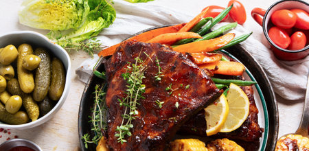 BBQ ribs with vegetables, sauce, roasted corn and watermelon on a white background. Top view. Copy space.の写真素材