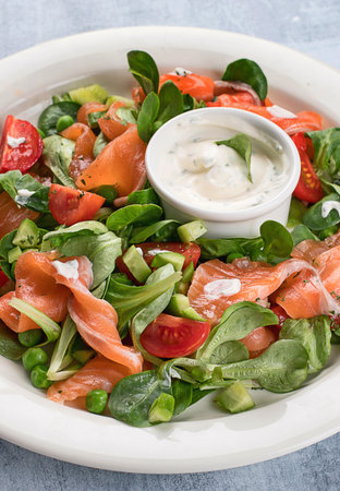 Vegetable salad with salmon and sauce on blue background. Healthy diet eating. Top view.の写真素材