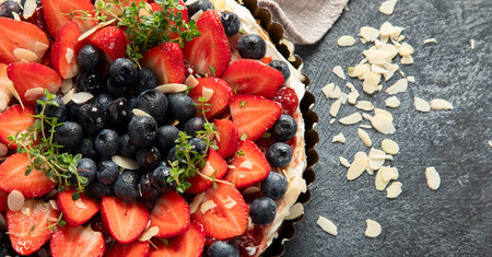 Delicious tart with fresh strawberries and blackberries on a gray background. Top view. Copy space.