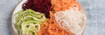 Vegetable noodles. Fresh zucchini, carrot, white radish, sweet potato and beet root pasta in a bowl. Top view. Panorama.の写真素材