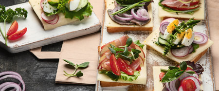 Assortment of open faced sandwiches on a white board on a black background. Top view. Panorama.の写真素材