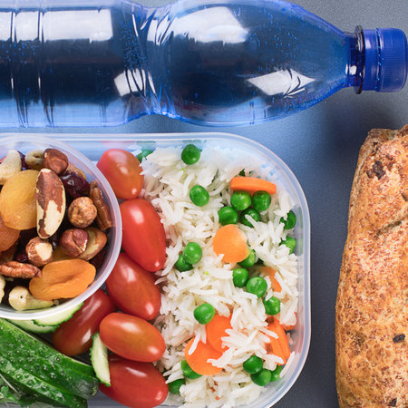 Healthy lunch boxes with rice, vegetables, nuts and bottle of water on a gray background. Top view.の写真素材