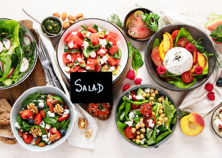 Various summer salads with strawberry, herbs. Healthy salad with arugula, peaches, burrata, blueberries and walnuts on a light background. Fresh healthy dish for healthy eating. Top view.の写真素材