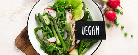 Fresh Green Asparagus salad with peas, radish, cucumber and lettuce on a light background. Top view. Panorama.の写真素材