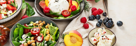 Various summer salads with strawberry, herbs. Healthy salad with arugula, peaches, burrata, blueberries and walnuts on a light background. Top view, copy space.の写真素材