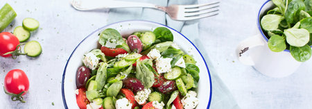 Fresh vegetable salad with feta cheese in a plate on a blue background. Traditional Greek salad. Top view.の写真素材