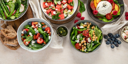 Various summer salads with strawberry, herbs. Healthy salad with arugula, peaches, burrata, blueberries and walnuts on a light background. Fresh healthy dish for healthy eating. Top view. Copy space.の写真素材
