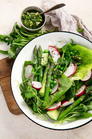 Fresh Green Asparagus salad with peas, radishe, cucumber and lettuce on a light background. Top view.の写真素材