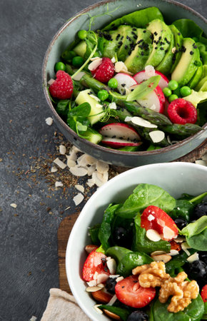 Fresh vegan summer salads with vegetables, fruits and nuts on a dark background. Top view.の写真素材