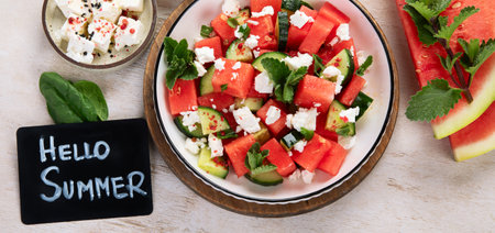 Watermelon summer salad with feta cheese, cucumber and mint on a light background. Healthy eating. Top view.の写真素材