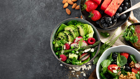 Fresh vegan summer salads with vegetables, fruits and nuts on a dark background. Top view. Copy space.の写真素材