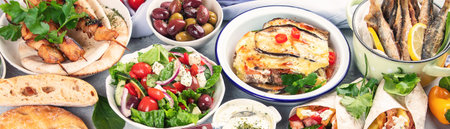 Greek food on gray background. Moussaka, gyros, souvlaki, pita, salad, olives and vegetables. Traditional different types of Greek dishes. Panorama, bannerの写真素材