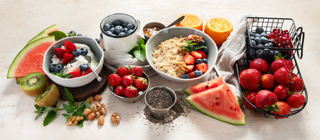 Organic ingredients for healthy breakfast - yoghurt, nuts, fresh fruits, oatmeal, whole grain flakes on white background. Top view.の写真素材
