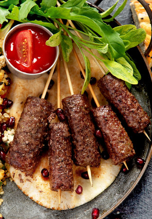 Grilled Turkish Kebab with sauce and rice on plate on a dark background. Adana durum. Top view