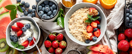 Organic ingredients for healthy breakfast - yoghurt, nuts, fresh fruits, oatmeal, whole grain flakes on white background. Top view. Panorama.の写真素材