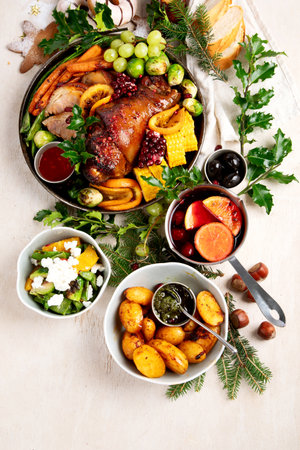 Holiday feast with roasted pork, vegetables, wine and desserts served on a light background. Top view.の写真素材