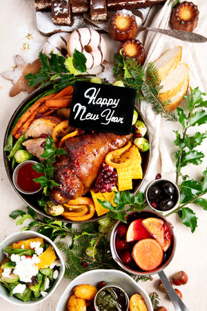 Holiday feast with roasted pork, vegetables, wine and desserts served on a light background. Top view.の写真素材