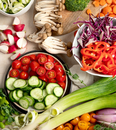 Fresh chopped vegetables on a plate and in bowls. Vegetarian, vegan food on a light background. Top...