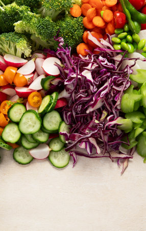 Variety of fresh chopped vegetables: carrots, cucumber, red bell pepper, tomato, salad, onion on a light background. Top view. Copy space.の写真素材