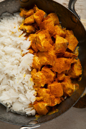 Hot spicy chicken tikka masala in bowl on a dark background. Chicken curry with rice, bread and herbs. Traditional Indian dish. Top view.の写真素材