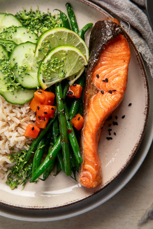 Fried salmon fish fillets with rice, vegetables and lime on a plate on a light background. Top view.の写真素材