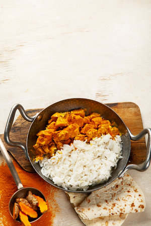 Hot spicy chicken tikka masala in bowl on a dark background. Chicken curry with rice, bread and herbs. Traditional Indian dish. Top view.の写真素材