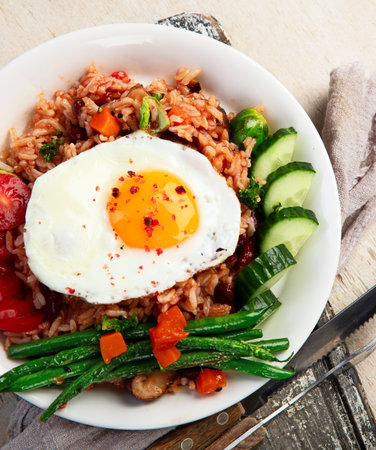 A plate of Nasi Goreng with rice, vegetables, and an egg on top on a light background. Top view.の写真素材