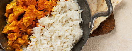 Hot spicy chicken tikka masala in bowl on a dark background. Chicken curry with rice, bread and herbs. Traditional Indian dish. Top view.の写真素材