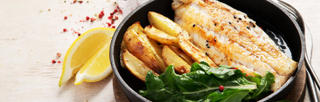 Fish dish - roasted cod, codfish fillet with baked potatoes and salad on a light background. Top view. Panorama with copy space.の写真素材