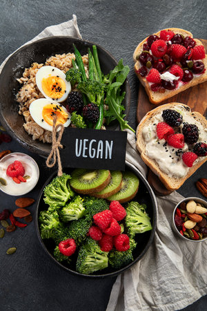 Bowls of porridge with eggs and vegetables, sandwiches with fruits. Healthy eating. Top view.の写真素材